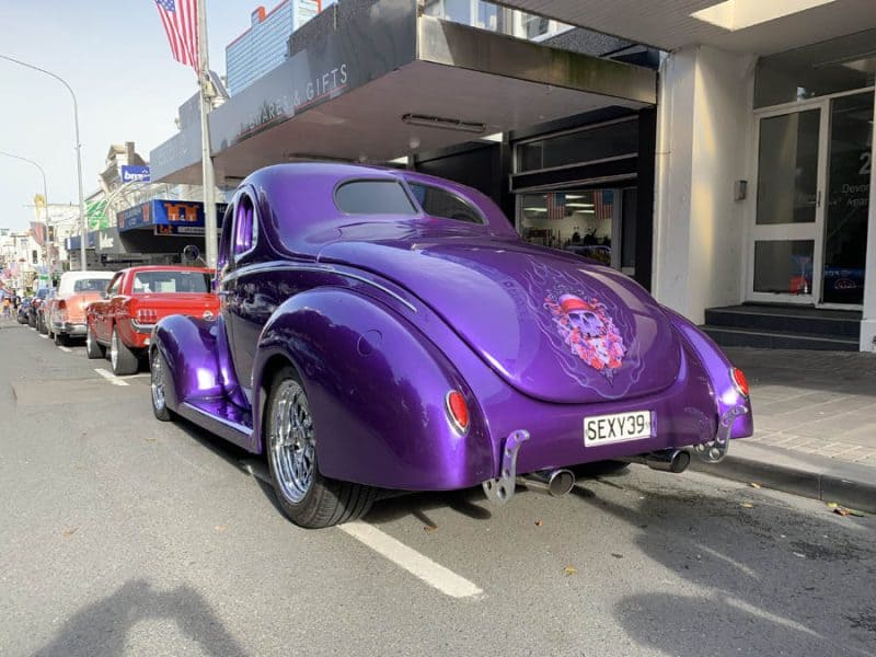 Bright purple classic car with skull and flower decal at Americarna festival.