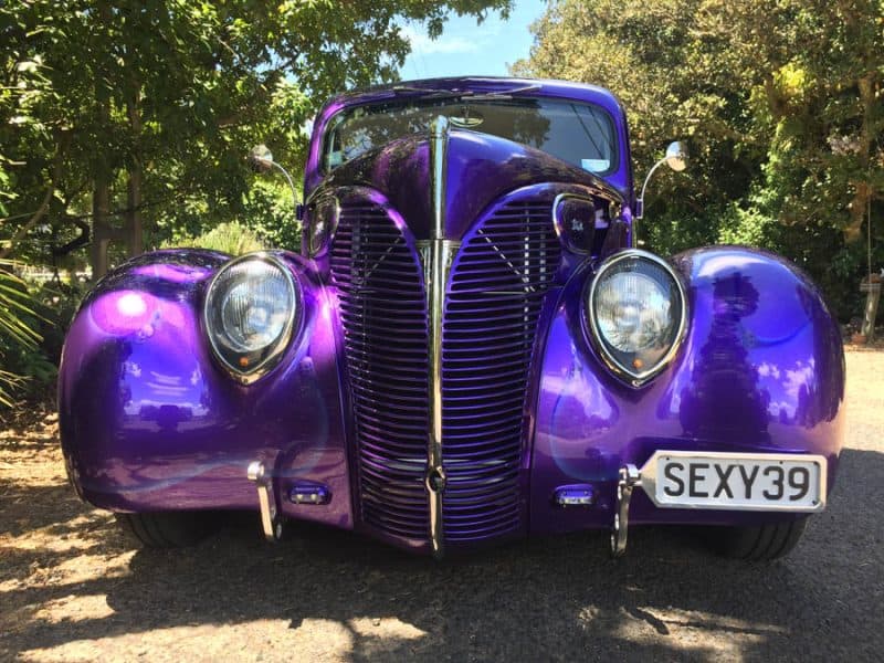 Bright purple classic car with unique design at American car show, parked outdoors.