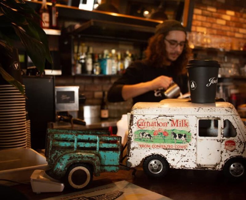 Rustic toy dairy truck decor at Americarna, New Zealand motor vehicle event; vintage style with cows and milk.