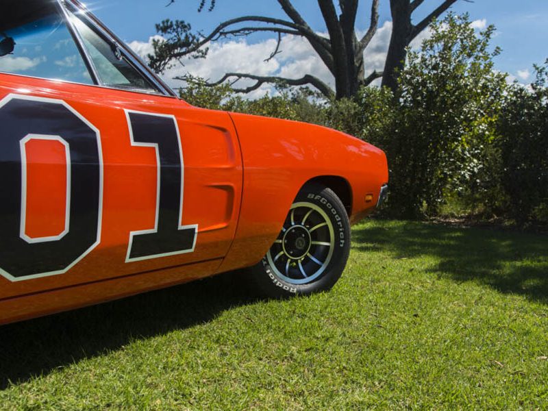 Bright orange vintage race car with racing number D1 on lush green grass.
