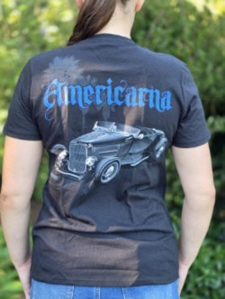 Woman wearing Americarna T-shirt featuring a vintage car graphic outdoors.
