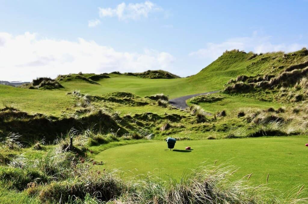 Lush green golf course with dunes.