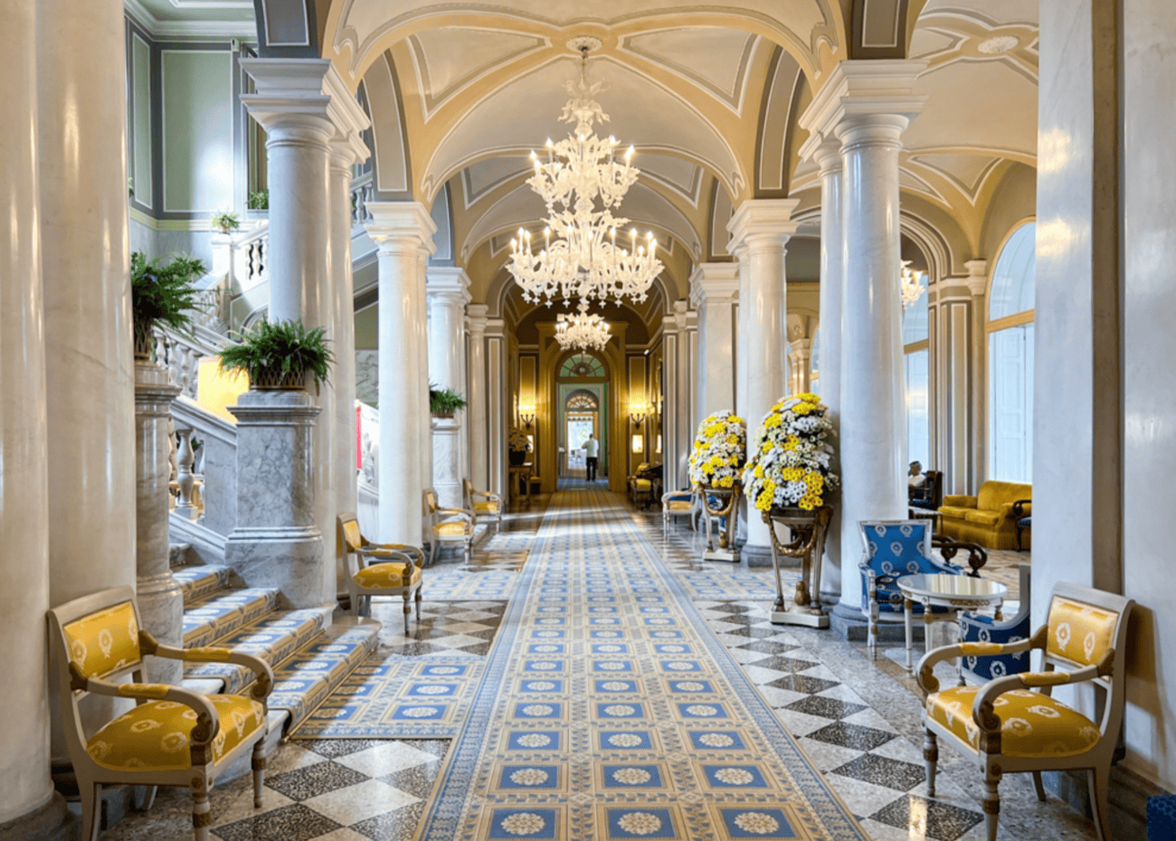 Luxurious hotel lobby with chandeliers, marble columns, and elegant seating areas.