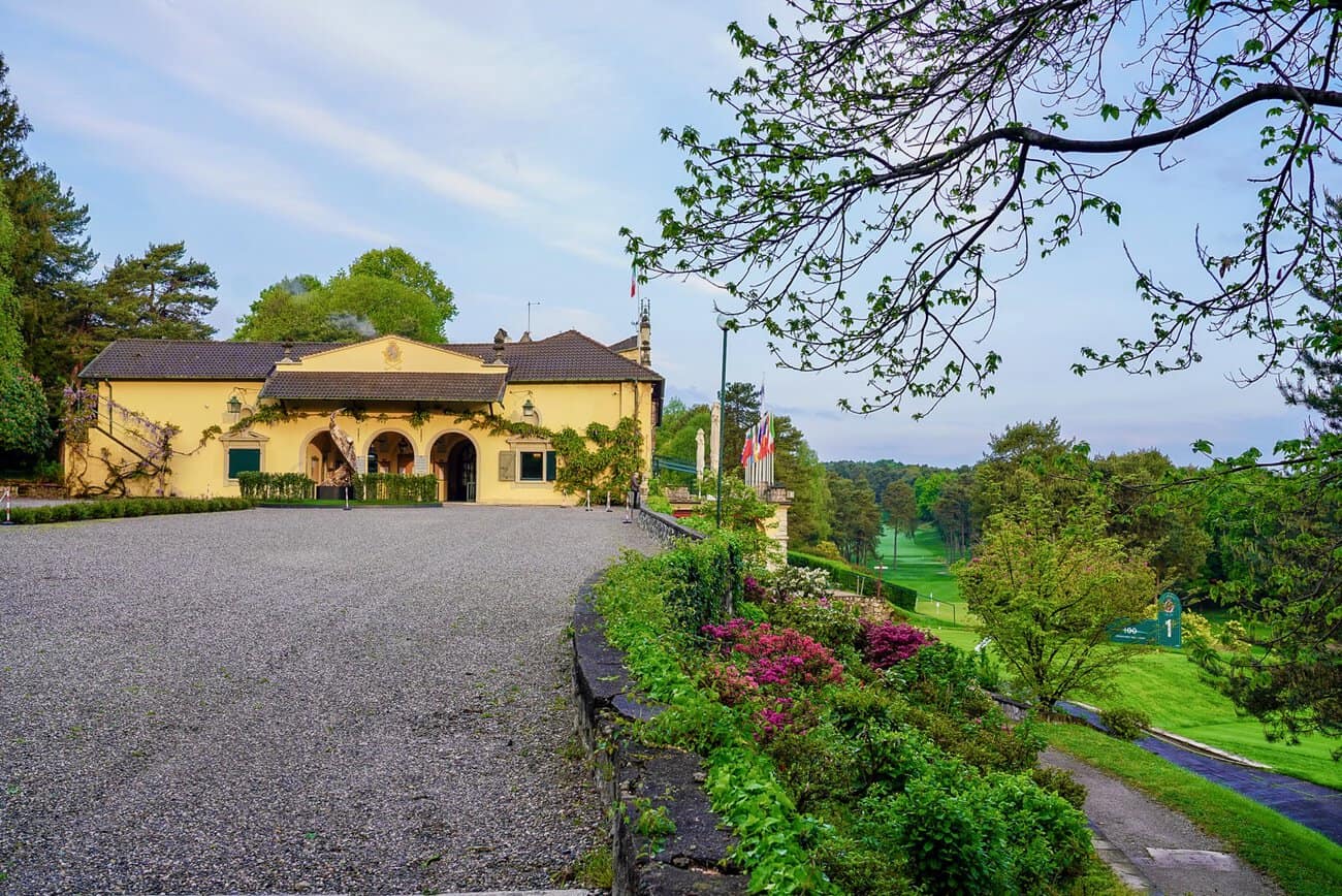 Scenic view of Villa d' Este Golf Club with lush greenery and a yellow building.
