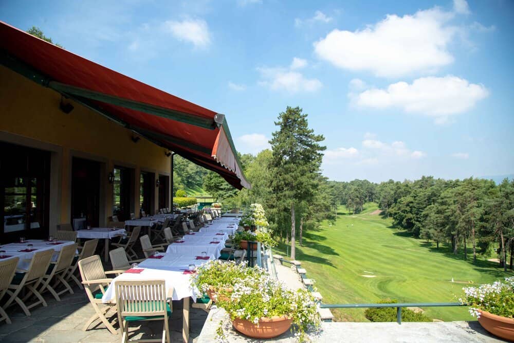 Scenic view of Villa d' Este Golf Club with outdoor dining area and lush green course.