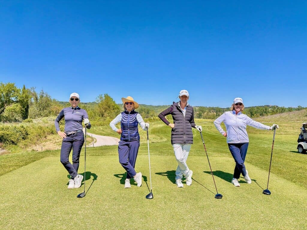 Group of four women playing golf on a sunny day at the golf course.