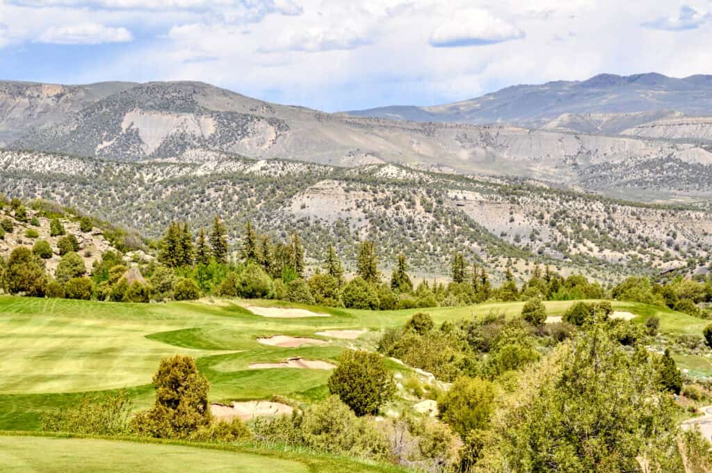 Scenic view of a golf course with mountains in the background during daytime.