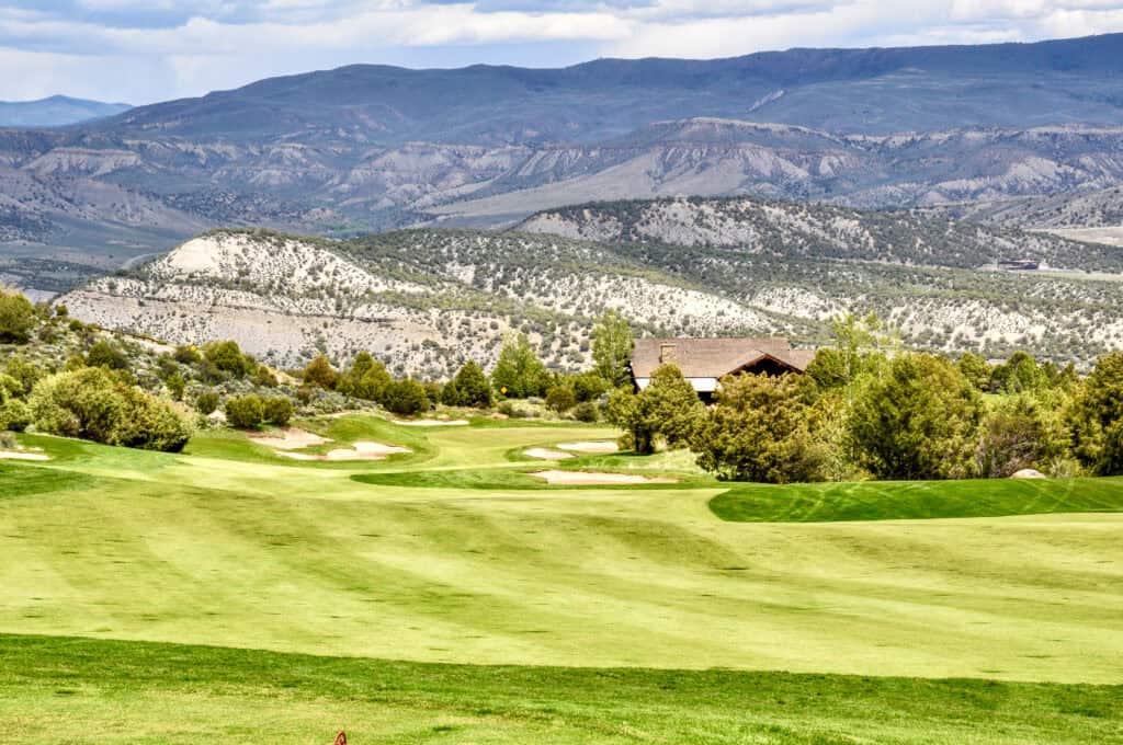 Scenic view of a golf course with mountains in the background and lush greenery.