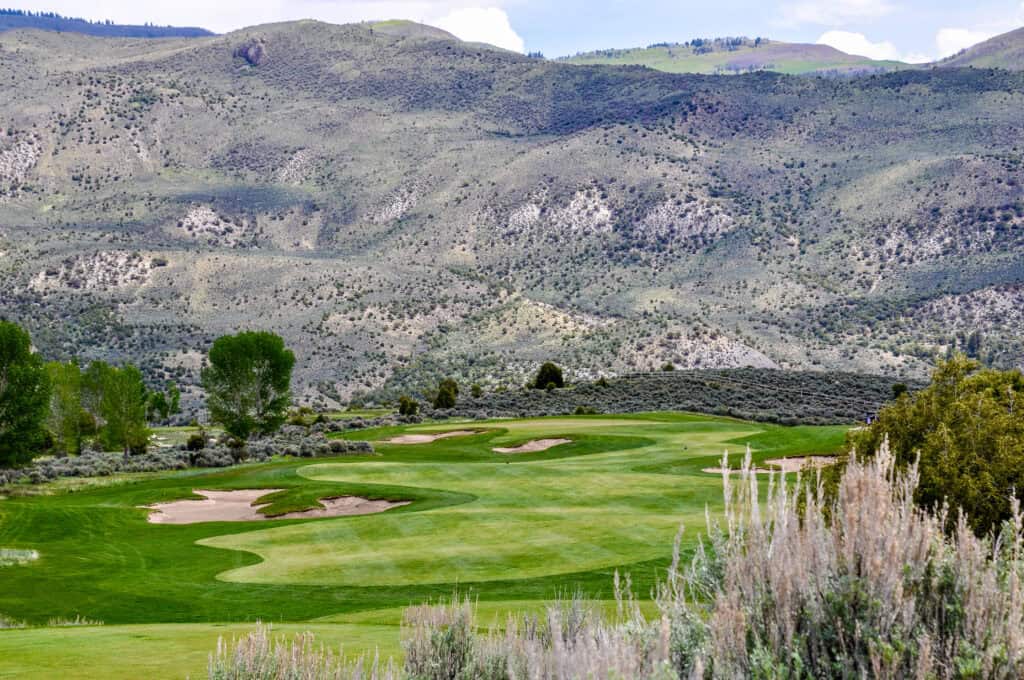 Scenic golf course with mountains and greenery in the background.
