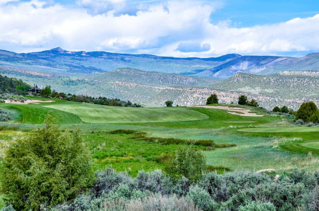 Scenic view of a lush golf course with mountains in the background.