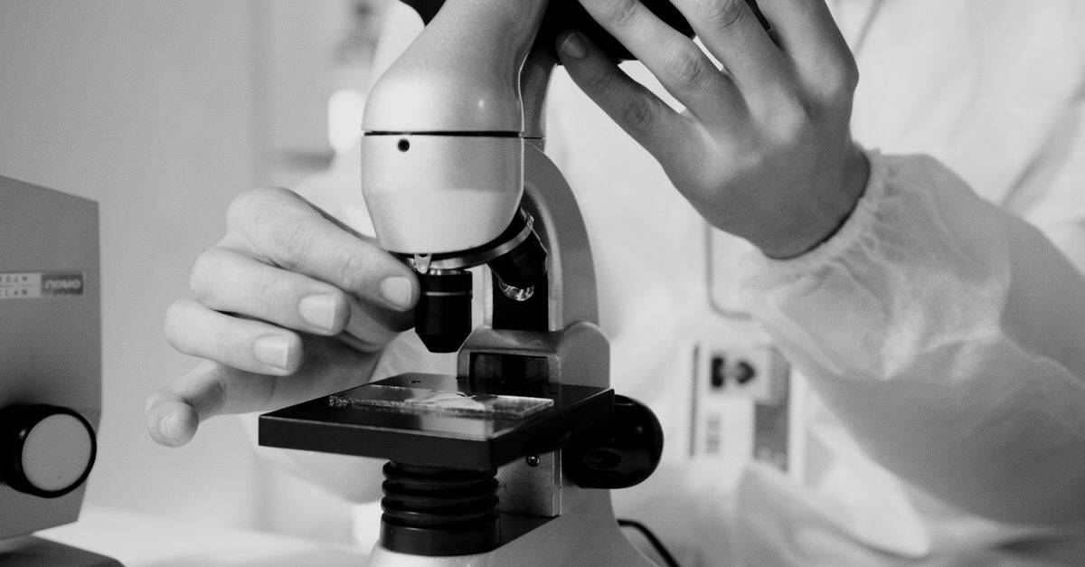 A scientist examining samples under a microscope in a laboratory setting, emphasizing scientific research and precision in health and nutrition testing.