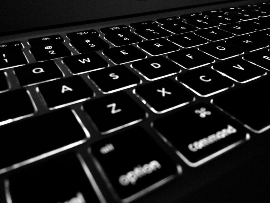 Clavier d'ordinateur rétroéclairé en noir et blanc, mettant en valeur les touches illuminées, idéal pour le travail ou la programmation.