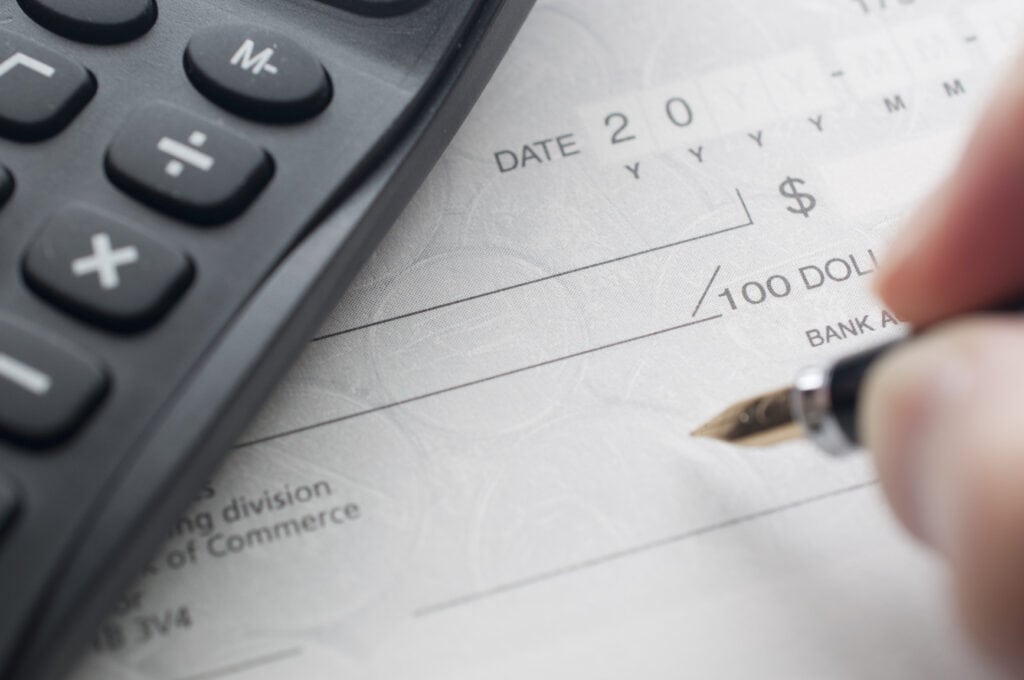 Calculatrice financière sur un chèque de paye, indiquant la gestion des finances personnelles et les conseils d'investissement.