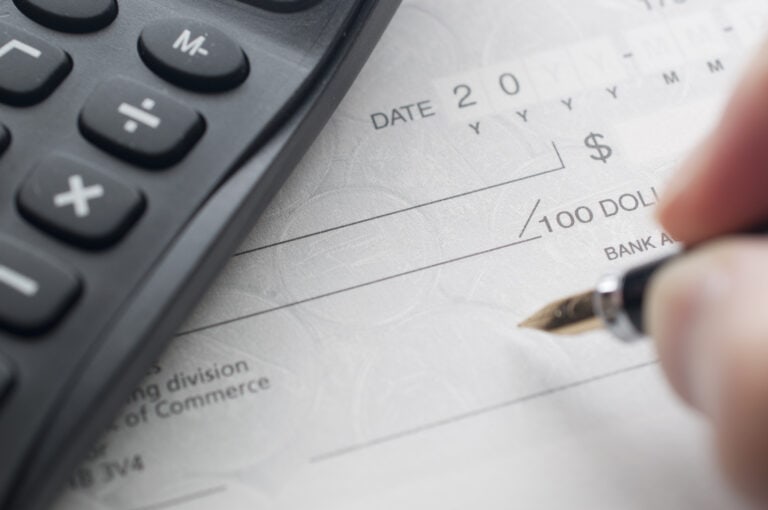 Calculatrice financière sur un chèque de paye, indiquant la gestion des finances personnelles et les conseils d'investissement.