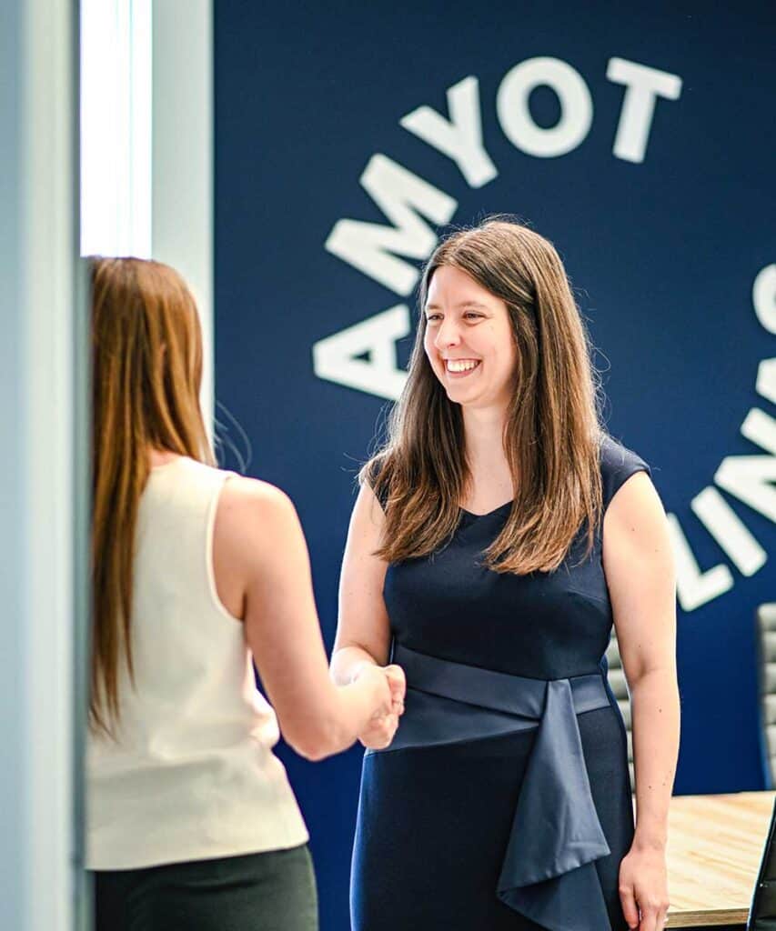 Chancelière professionnelle félicitant une collègue dans un environnement de bureau moderne et dynamique, symbolisant la collaboration et le succès professionnel.