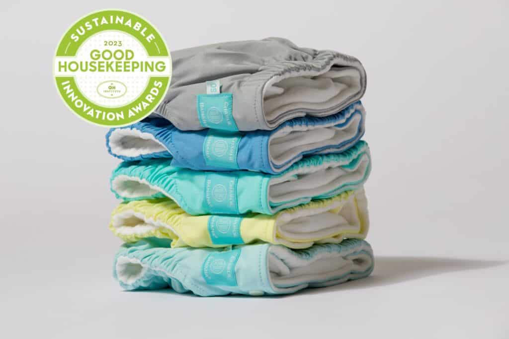 A stack of colorful Charlie Banana cloth diapers with a Good Housekeeping Sustainable Innovation badge.