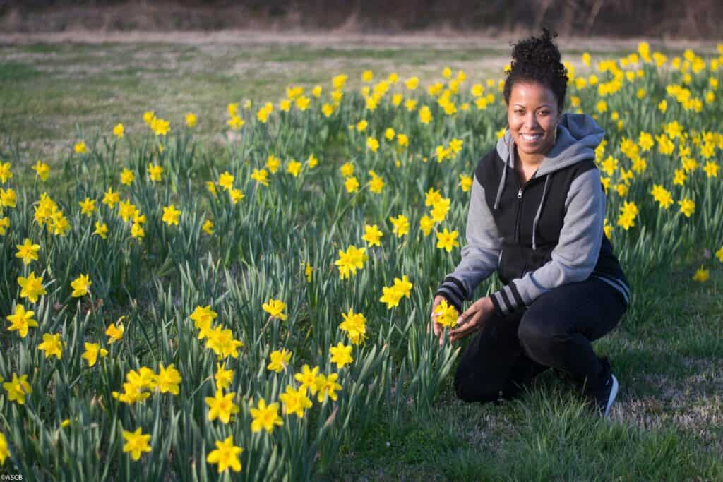 Ana standing in a field of flowers, symbolizing growth and empowerment