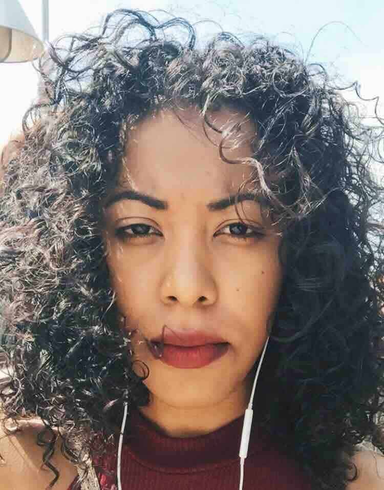 Smiling woman with curly hair wearing a red top, natural beauty