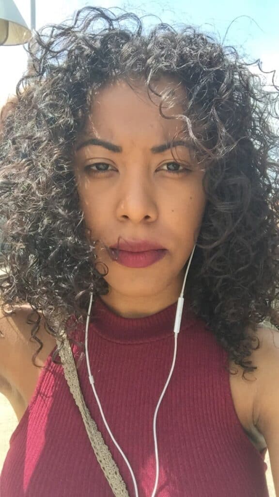 Outdoor selfie with natural light highlighting soft, frizz-free curls styled with curl control cream.