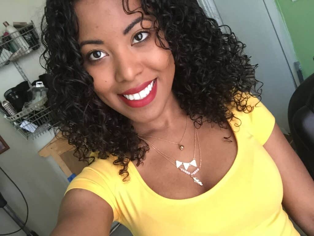 Smiling selfie featuring glossy, freshly styled curls with red lipstick and defined curl pattern.