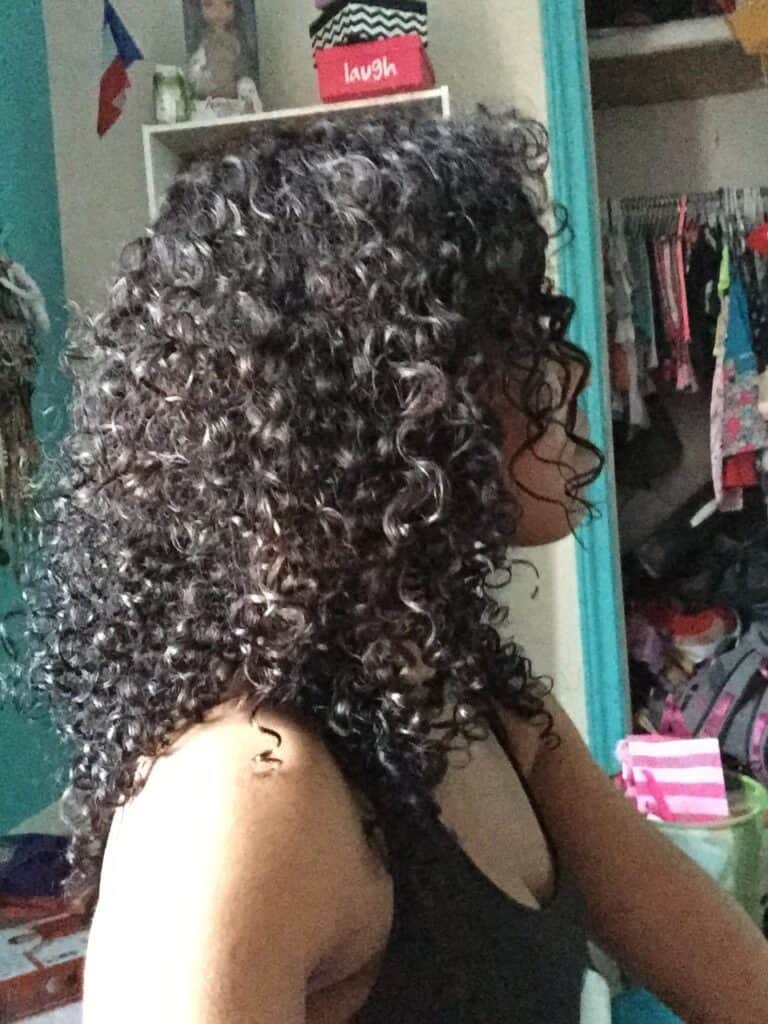 Side profile of a woman with defined, voluminous curls styled using Obliphica products.