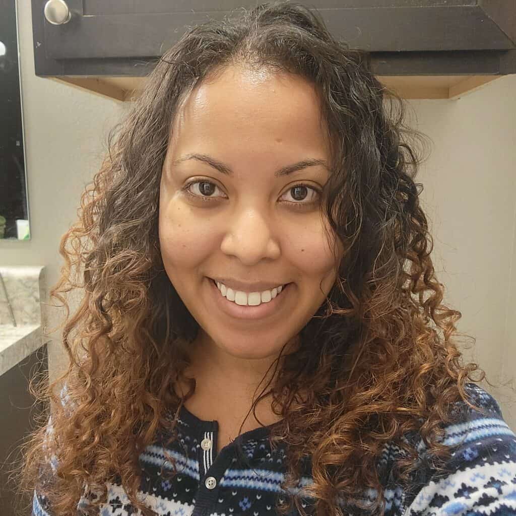 Smiling woman with long, defined curls, months before her big chop.