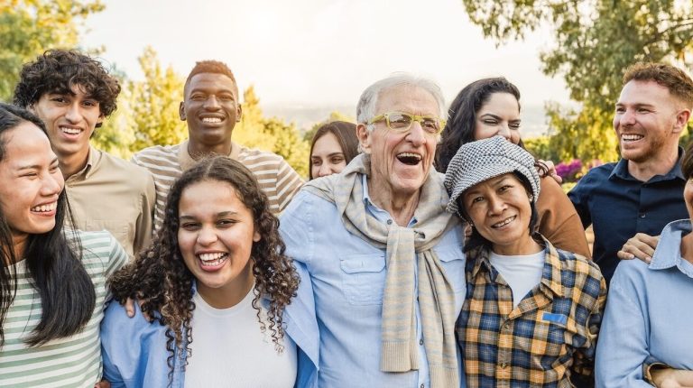 Group of multigenerational people smiling in front of camera Multiracial friends of different ages having fun together Main focus on caucasian senior face