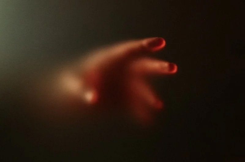 a blurry image of a person's hand with red nails