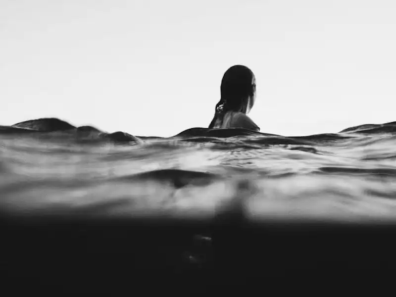 Artistic black and white photo of a woman swimming at dusk, creating a serene and adventurous mood.