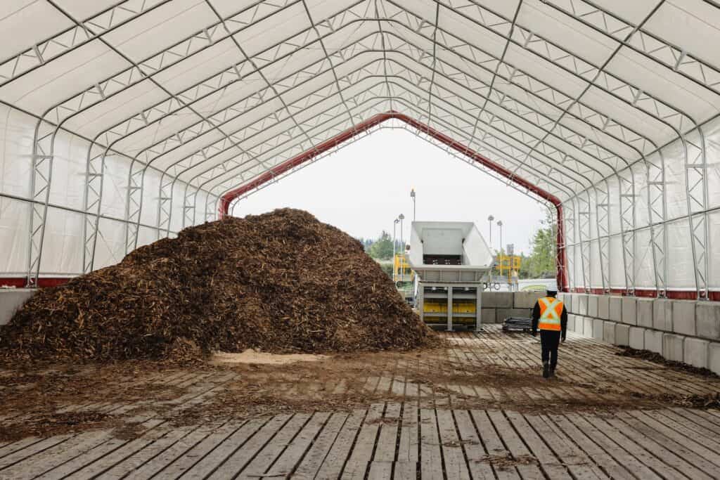 A man walks toward a feedstock pile at the Arbios Chuntoh Ghuna facility