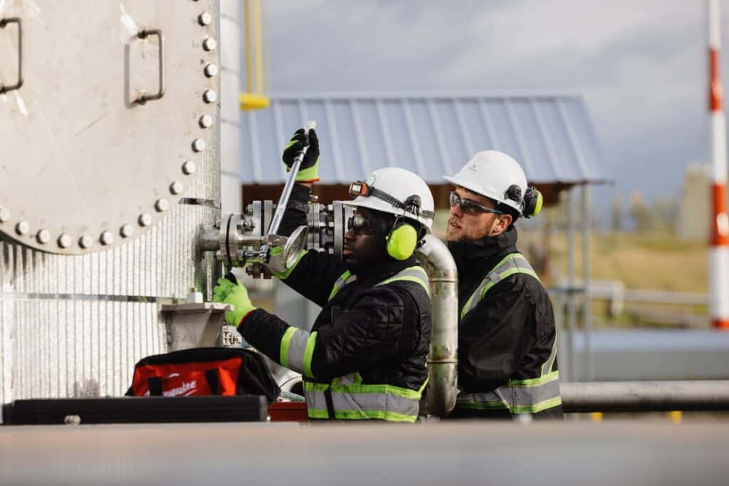 Two people tighten a pressure gauge at the Arbios Chuntoh Ghuna facility