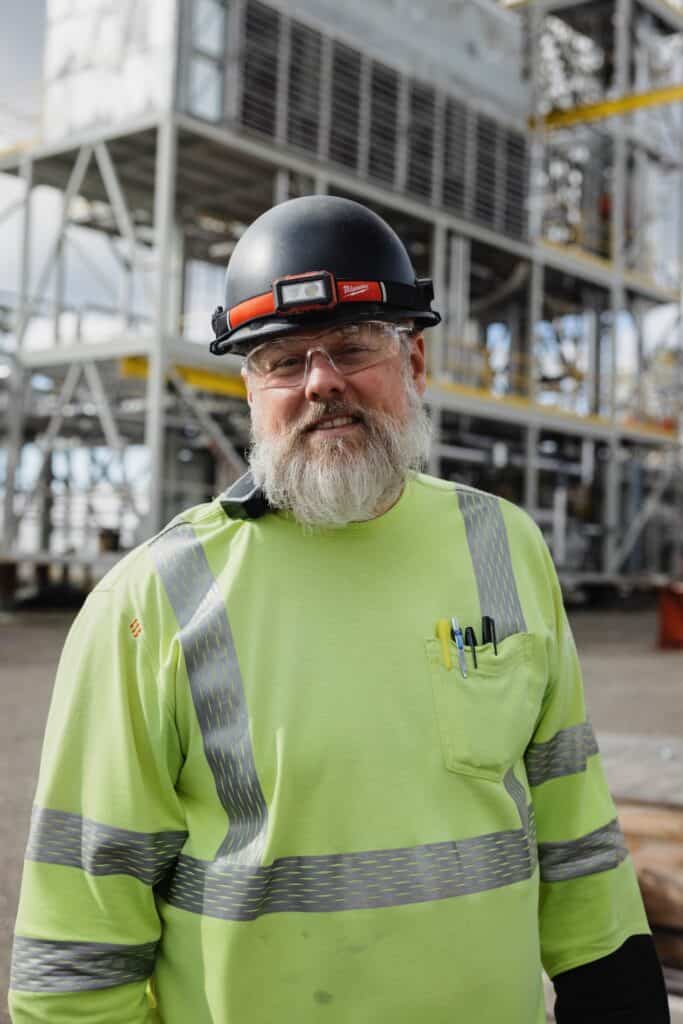A man in a hard hat looks at the camera