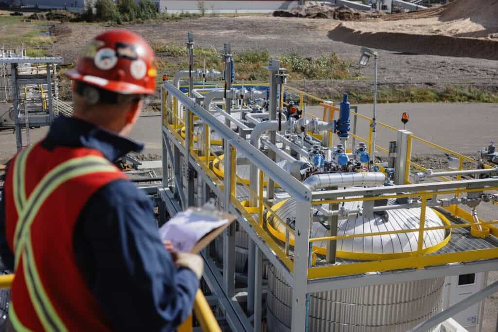 a man in a hard hat standing next to a large metal structure at the Arbios Chuntoh Ghuna facility
