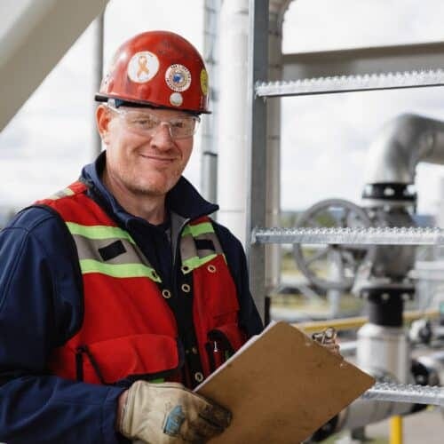 a man in a red hard hat holding a clipboard