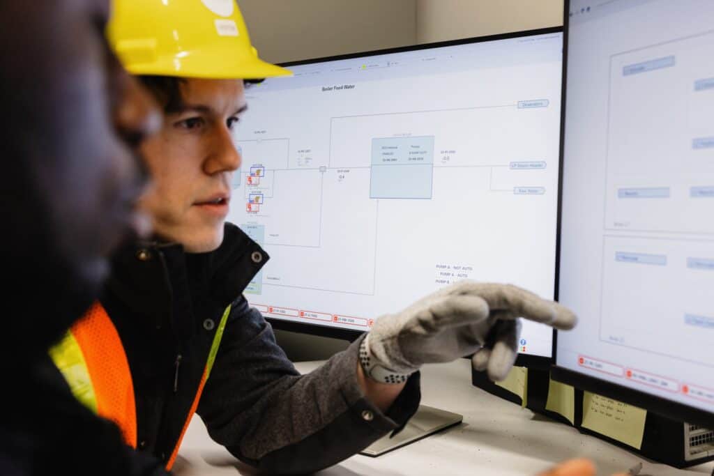 Two people point at the screen in a control room