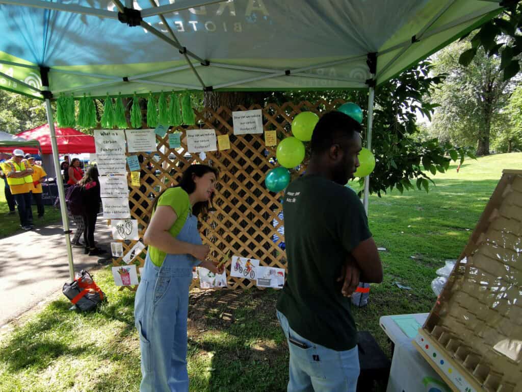 Members of Arbios stand at a booth under a tent