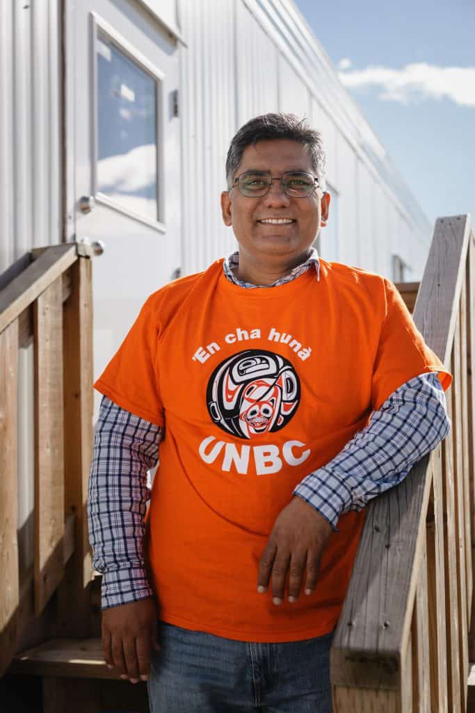 man standing outside Arbios office with orange UNBC shirt