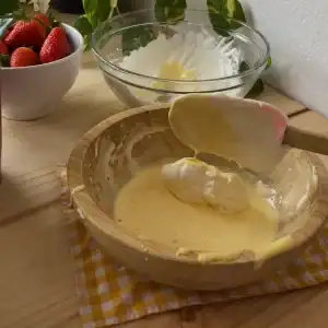 Mascarpone cheese, whipped cream, and beaten eggs being gently folded together to create a smooth, creamy layer for a strawberry tiramisu recipe