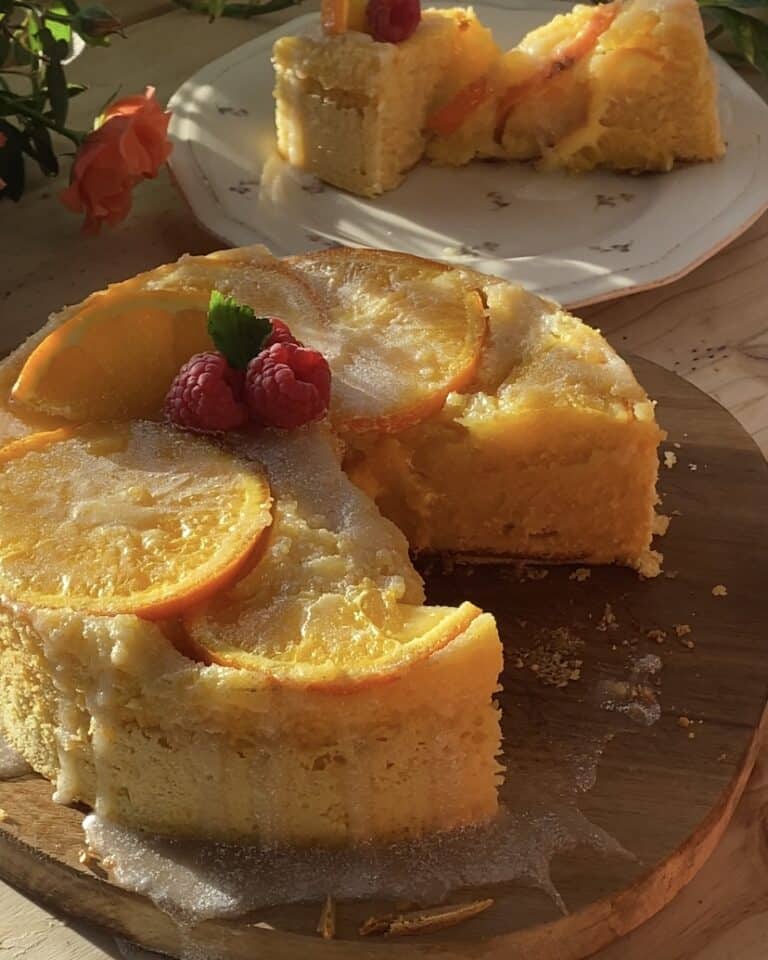 A beautifully moist upside-down orange cake with vibrant caramelized orange slices on top, displayed on a rustic wooden board, showcasing its golden, fluffy texture.