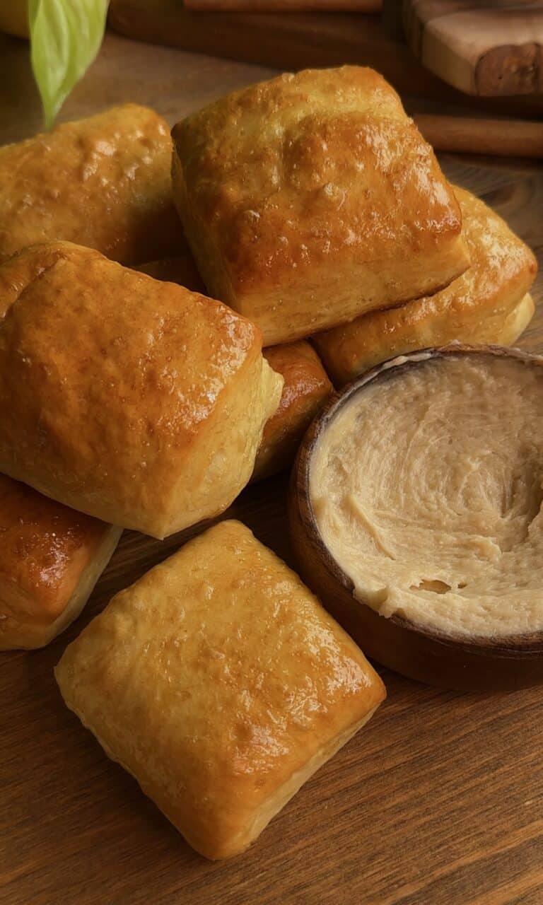 Fluffy Texas Roadhouse rolls arranged around a bowl of creamy honey cinnamon butter in the center, golden brown and perfect for dipping