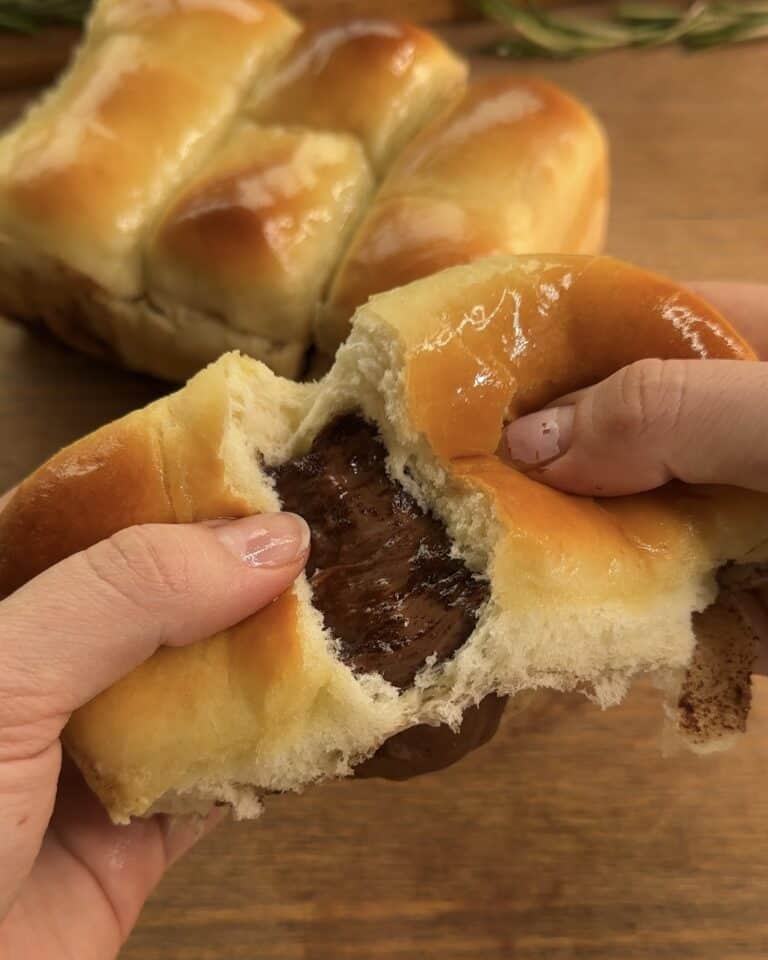 Nutella-stuffed brioche cut open in half, revealing its fluffy, golden interior filled with creamy, rich Nutella