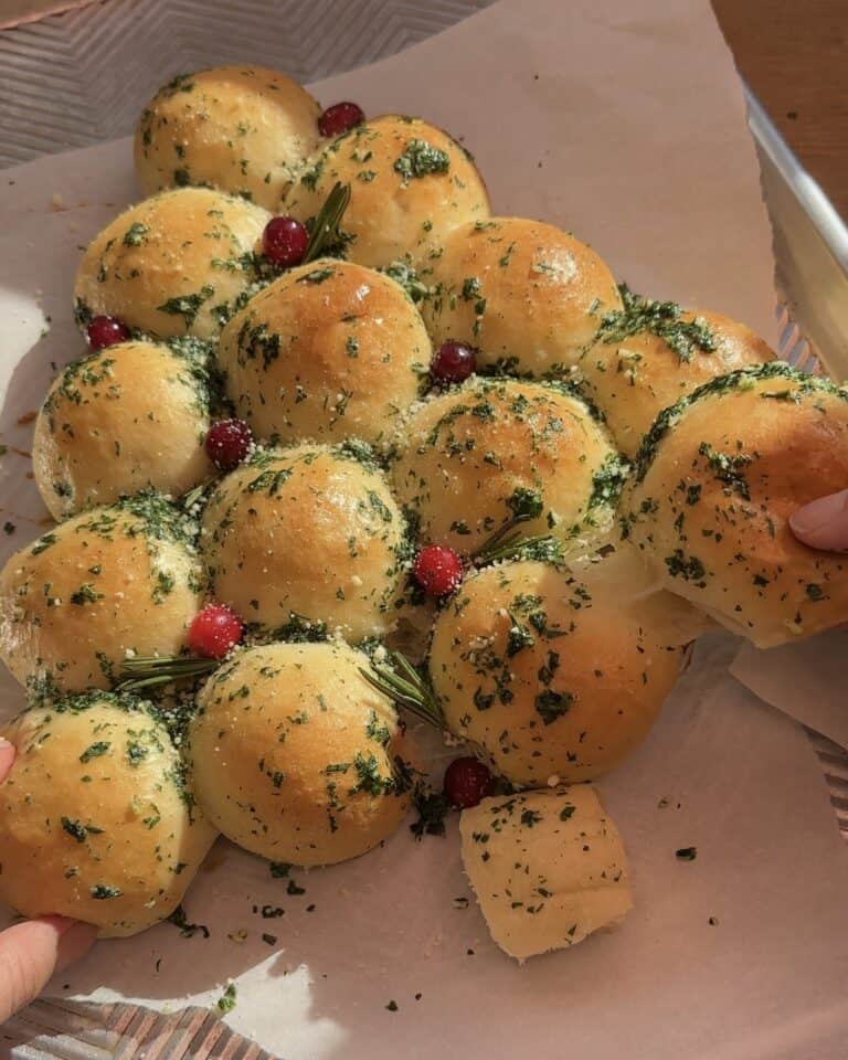 Grabbing one of the dough balls from the pull-apart Christmas tree garlic bread, still attached to the rest of the bread, ready to be pulled apart and enjoyed.