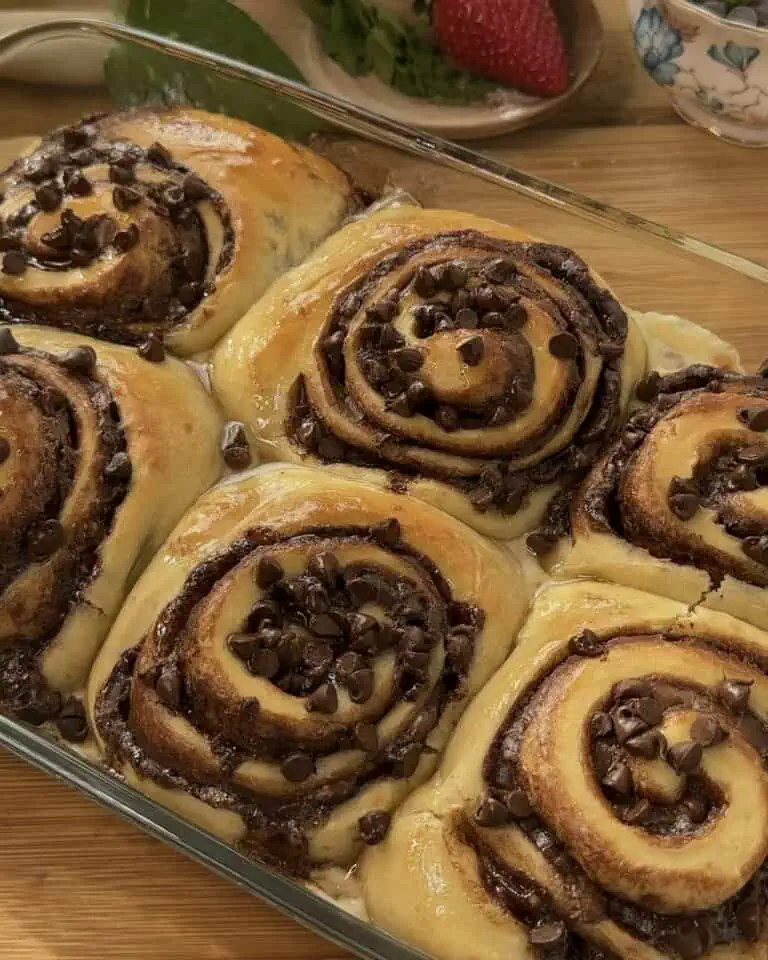 Golden-brown Nutella rolls fresh out of the pan, showcasing a gooey chocolate center and topped with melting chocolate chips for a delicious, indulgent treat.