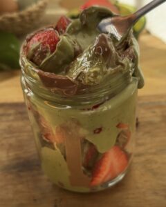 "Close-up of a fork digging into a jar filled with Dubai chocolate strawberries, revealing the layers of kataifi pastry, pistachio cream, and melted chocolate. A juicy strawberry covered in the creamy pistachio mixture is perfectly visible, with the kataifi adding a crunchy texture, making each bite a delightful blend of flavors and textures."