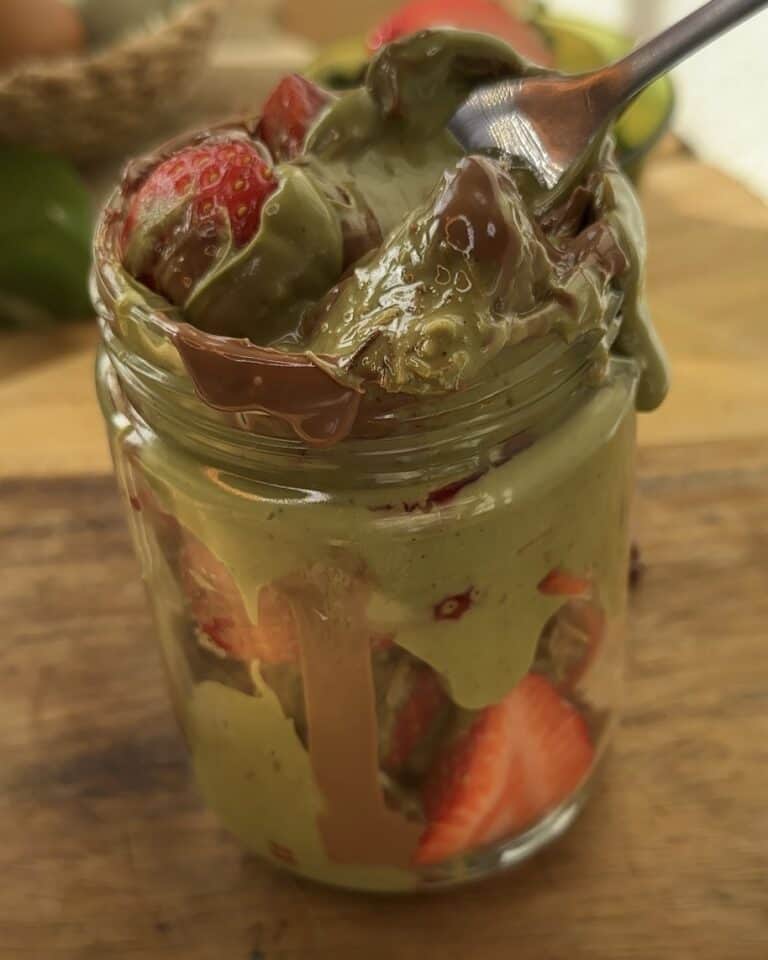 "Close-up of a fork digging into a jar filled with Dubai chocolate strawberries, revealing the layers of kataifi pastry, pistachio cream, and melted chocolate. A juicy strawberry covered in the creamy pistachio mixture is perfectly visible, with the kataifi adding a crunchy texture, making each bite a delightful blend of flavors and textures."