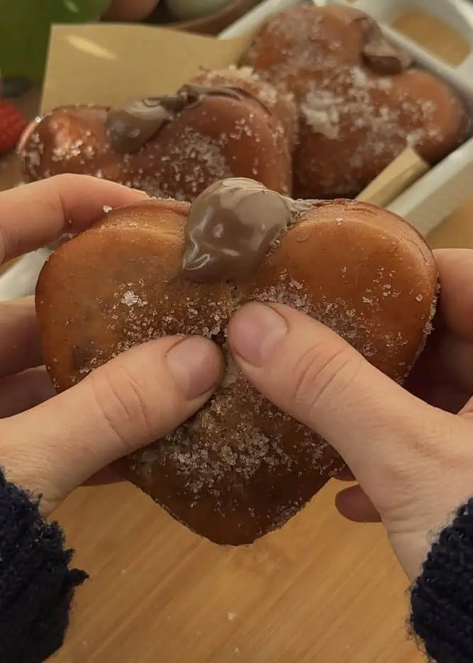 Heart-shaped Nutella donut cut in half, showing oozing Nutella filling and fluffy texture.