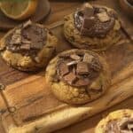 Homemade Copycat Crumbl KitKat cookies with a gooey texture, KitKat pieces inside, a rich chocolate spread on top, and extra KitKats for decoration.