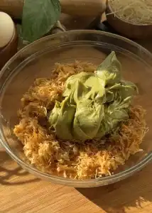 Toasted kataifi in a bowl topped with pistachio cream, ready to be mixed for a rich and crunchy filling.