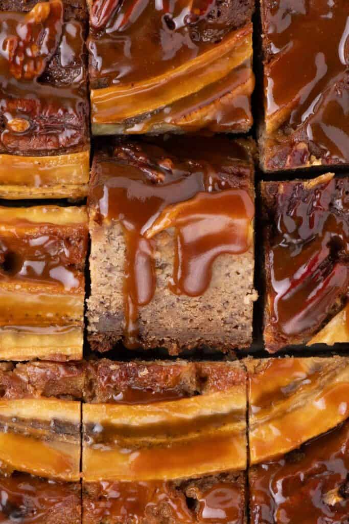 Overhead view of neatly sliced banana bread bars with caramel drizzle and banana decoration.