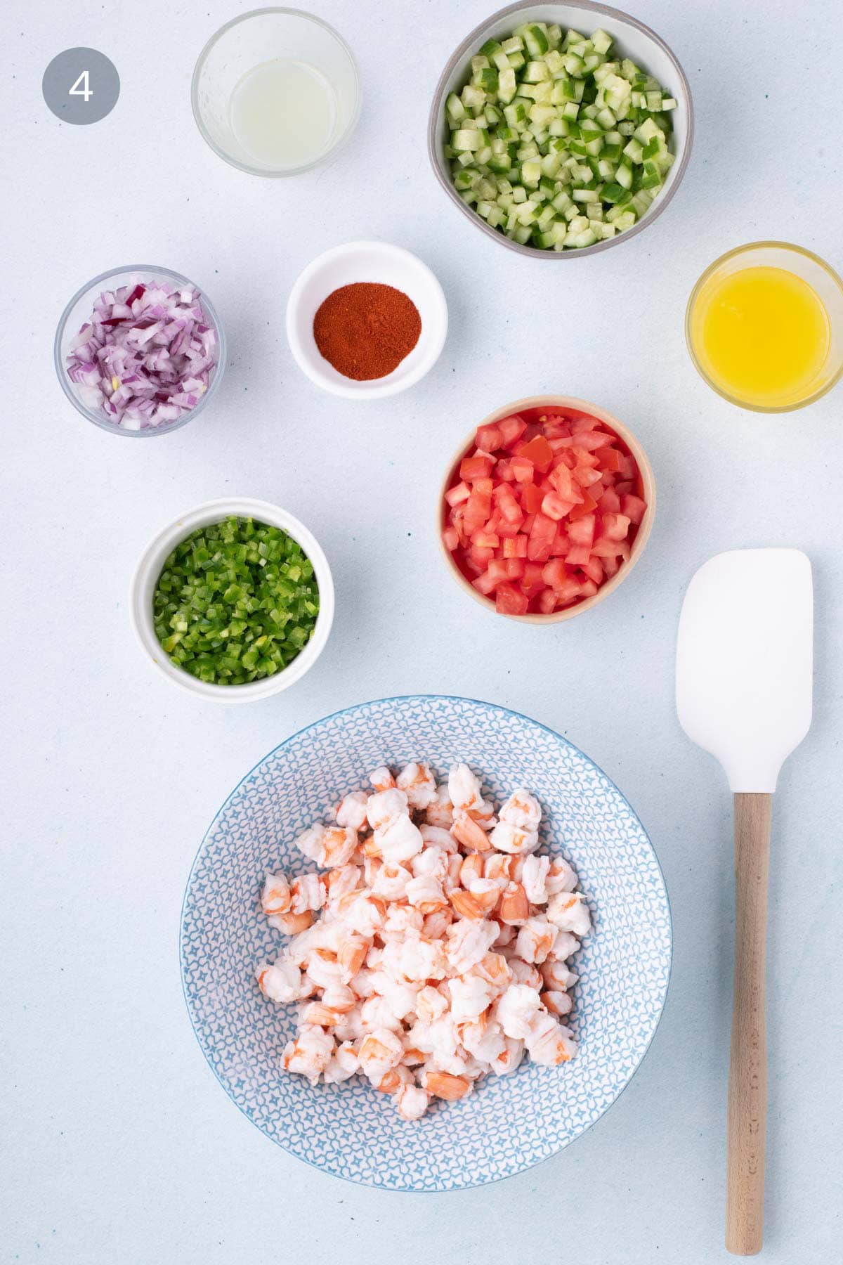 Ingredients for shrimp ceviche recipe including red onion, lime juice, smoked paprika, serrano peppers, tomato, cucumber, and orange juice